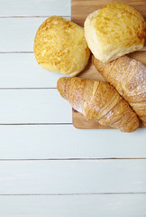 Freshly baked croissants and bread rolls arranged on a wooden breakfast table background forming a page header