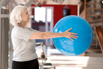 Smiling happy pleasant woman doing exercises with fit ball.