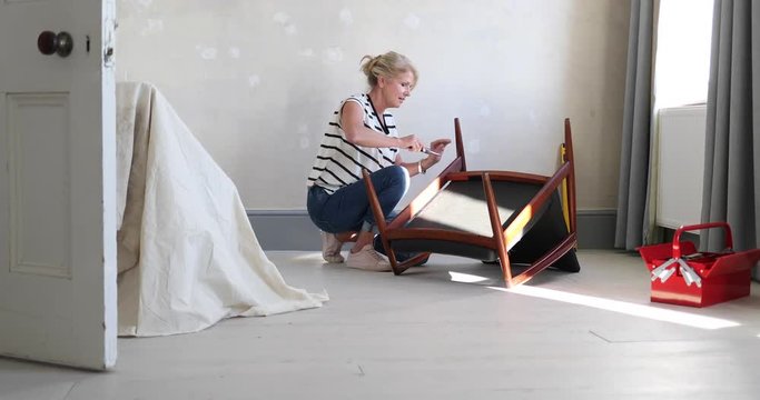 Mature female repairing an old chair