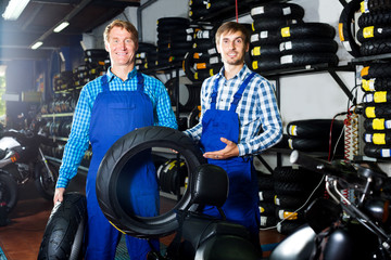 Two male professionals standing with new tires
