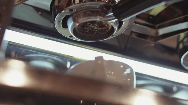 Barista makes coffee, it is pouring from the coffee makers filter into the white cup, coffees aroma spreading in the cafe. Baristas portrait. Inside shooting, cafe settings on the background.