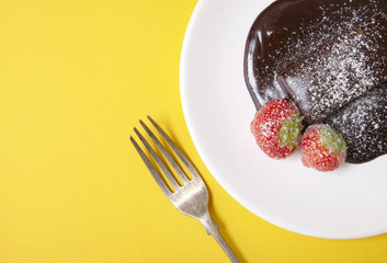 A chocolate fudge cake dessert on a  bright yellow background forming a page border