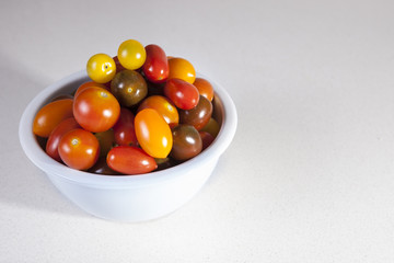 Clay bowl full of several varieties of cherry tomatoes