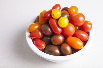 Clay bowl full of several varieties of cherry tomatoes
