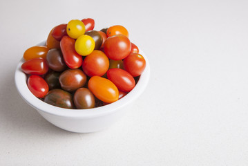 Clay bowl full of several varieties of cherry tomatoes