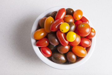 Clay bowl full of several varieties of cherry tomatoes
