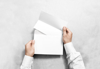 Hand holding white blank envelope and folded leaflet mockup, isolated. Arm hold empty brochure...