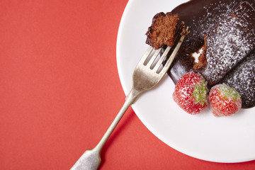 A chocolate fudge cake dessert on a bright red background forming a page border