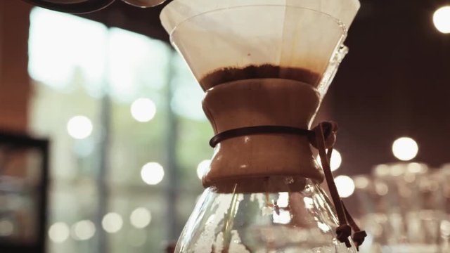 Close up of a barista making hand brewed coffee. Adding grinded coffee and pouring hot water. Baristas portrait. Inside shooting. Cafe atmosphere. Cafe activities. Restaurant activities.