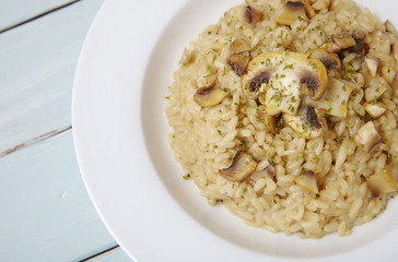 A dish of mushroom and chicken risotto rice on a rustic wooden table top background