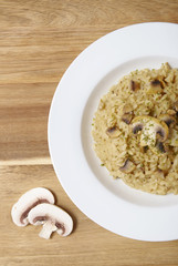 A dinner plate of chicken and mushroom risotto rice on a wooden counter top background