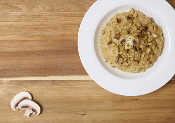 A dinner plate of chicken and mushroom risotto rice on a wooden table top background