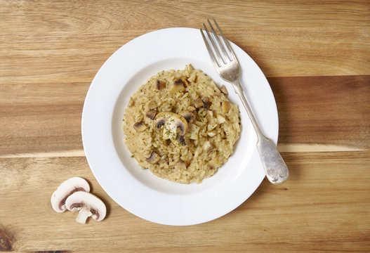 A Dinner Plate Of Chicken And Mushroom Risotto Rice On A Wooden Dining Table Background