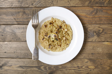 A dinner plate of chicken and mushroom risotto rice on a reclaimed wooden dining table background