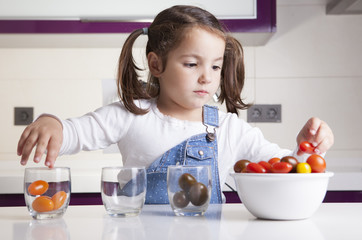 Little girl sorting by colors cherry tomatoes