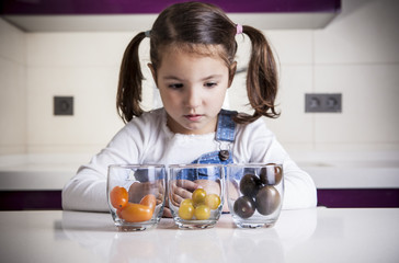 Little girl observing cherry tomatoes varieties colors - obrazy, fototapety, plakaty