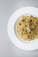 A dinner plate of chicken and mushroom risotto rice on a soft grey background