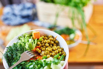 Vegetarian mix in a bowl with green peas, cucumbers, carrots, lettuce and dill, close up