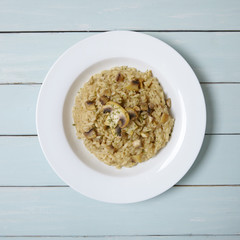 Aerial view of a bowl full of mushroom risotto rice on a blue wooden table top background