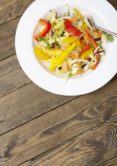 A bowl of fresh stir fry vegetables on a wooden dinner table background forming a page border