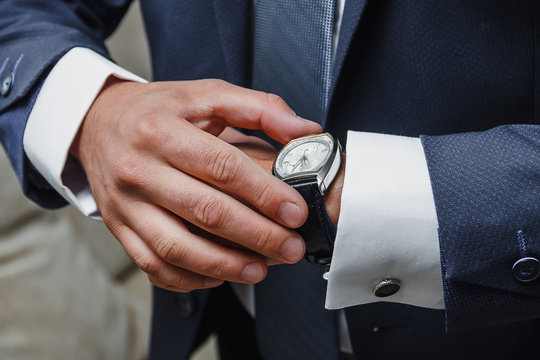 Close up of elegant man wearing suit checking the time with watch