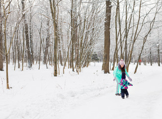 Fototapeta na wymiar Mother and little toddler girl walking in the winter forest and having fun with snow. Family enjoying winter. Christmas and lifestyle concept.