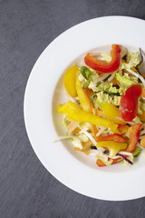 A bowl of fresh stir fry vegetables on a rustic slate background