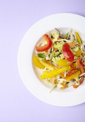 A bowl of fresh stir fry vegetables on a pastel purple background
