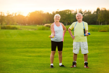 Senior couple with dumbbells. People smiling and doing exercise. Sport is in our blood. Strengthen joints and muscles.