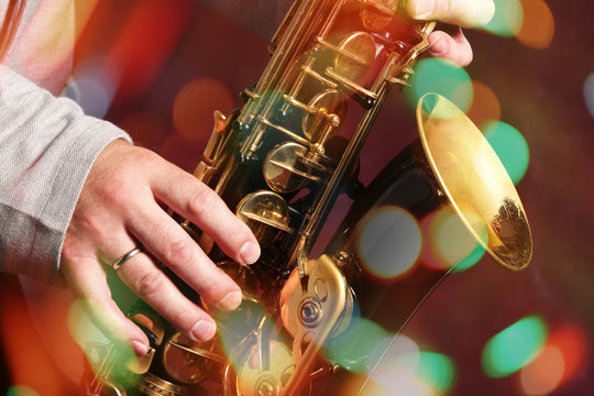 Man's Hands With Saxophone On Bokeh Lights