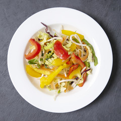 A bowl of fresh stir fry vegetables on a rustic slate background