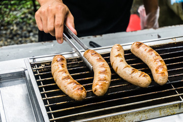 Fresh sausage and hot dogs grilling outdoors on a gas barbecue g