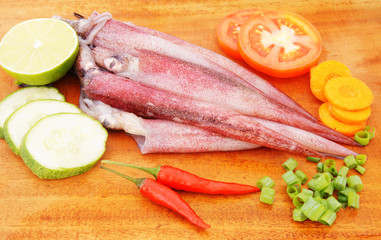 Cooking squids, squids and vegetables on wooden board