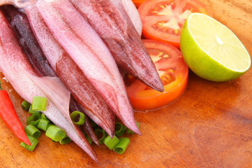 Cooking squids, squids and vegetables on wooden board