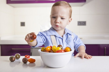 Baby boy holding a ripe colorful cherry tomatoe