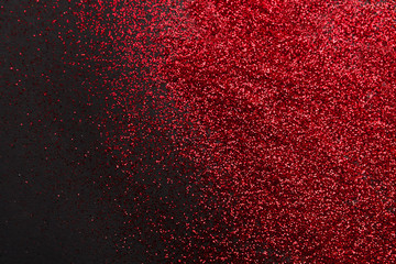 Red glitter sand texture on black, abstract background.