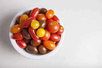Clay bowl full of several varieties of cherry tomatoes