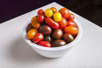 Clay bowl full of several varieties of cherry tomatoes