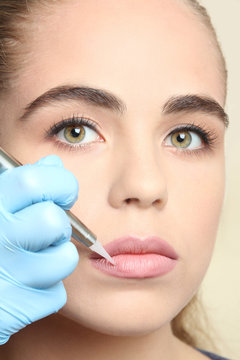Cosmetologist making permanent make up on lips