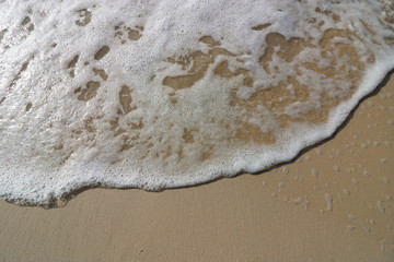 Wave and foam on the sand beach background