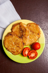 Potato pancakes with meat and tomatoes on green plate in Belarus