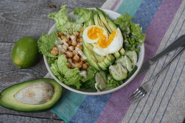 healthy salad in a bowl. avocado, chickpeas, cucumber and egg. more greens every day