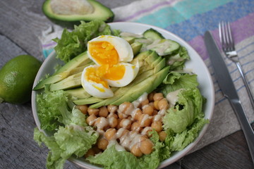 healthy salad in a bowl. avocado, chickpeas, cucumber and egg. more greens every day