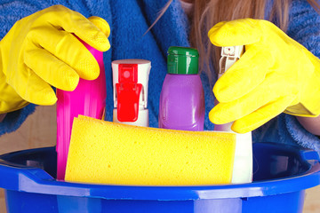 close-up of woman holdinh basin with cleaning supplies