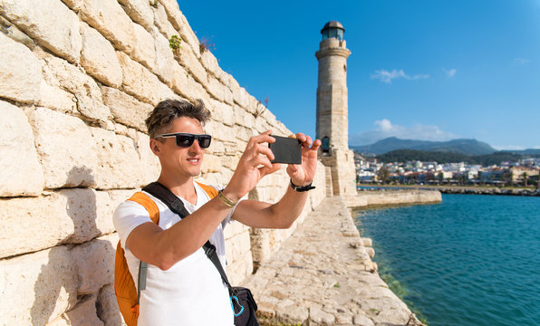 A guy taking a photo in front of the beautiful lighthouse in the Greek city Rethymnon