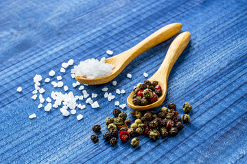 Salt crystals and color pepper on wooden spoons.