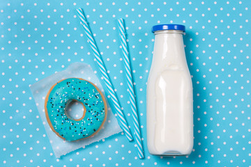 Blue donut, bottle of milk and straws on polka dots blue background