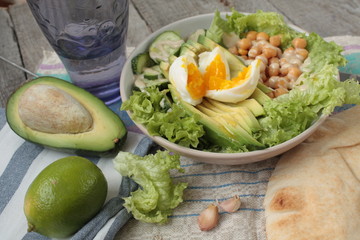 healthy salad in a bowl. avocado, chickpeas, cucumber and egg. more greens every day