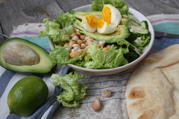 healthy salad in a bowl. avocado, chickpeas, cucumber and egg. more greens every day