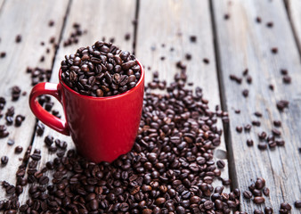 Coffee beans and red coffee cup on wooden background. Drink
